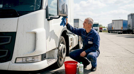 A telephelyen egy szakember éppen külsőleg tisztítja az egyik teherautót.