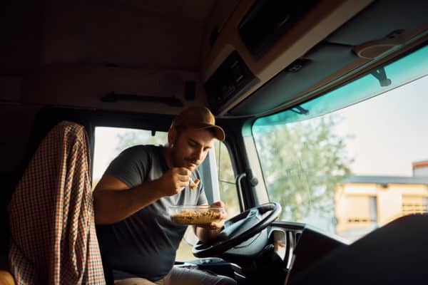 Young truck driver eating lunch inside of his vehicle