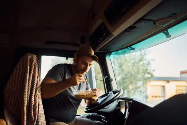 Young truck driver eating lunch inside of his vehicle 