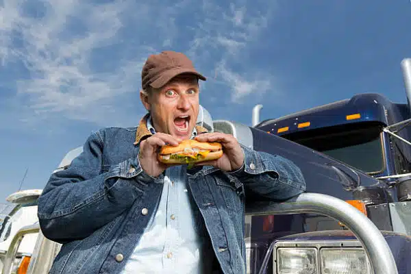 An image from the trucking industry of a truck driver eating a sandwich 